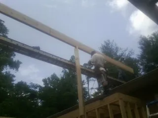 Carpenter setting a ridge beam over a new addition frame — Ice Dam Removal by Roofing Brothers in Etoile