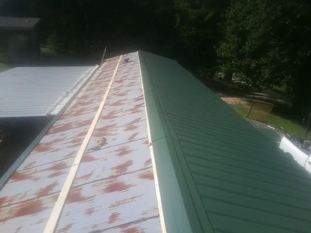 Old rusted panels beside newly installed green metal roofing — Wind Damage Roof Repair by Roofing Brothers in Etoile