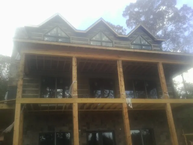 Dormers and porch framing on a large log home under construction — Roof Coating work by our crew in Etoile