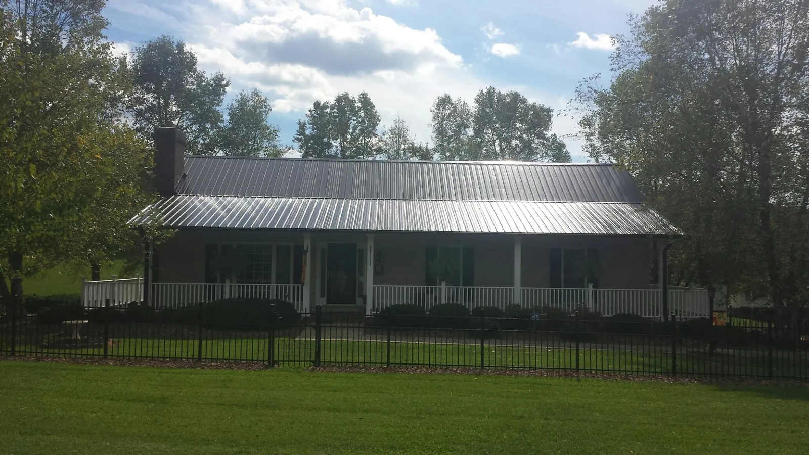 Gray metal roof on a brick ranch with a full width front porch — Gutter Guard Installation work by our crew in Etoile
