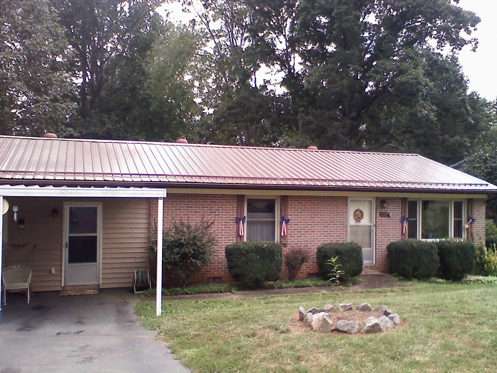 Bronze metal roof and carport on a brick ranch home — Roof Repair work by our crew in Etoile