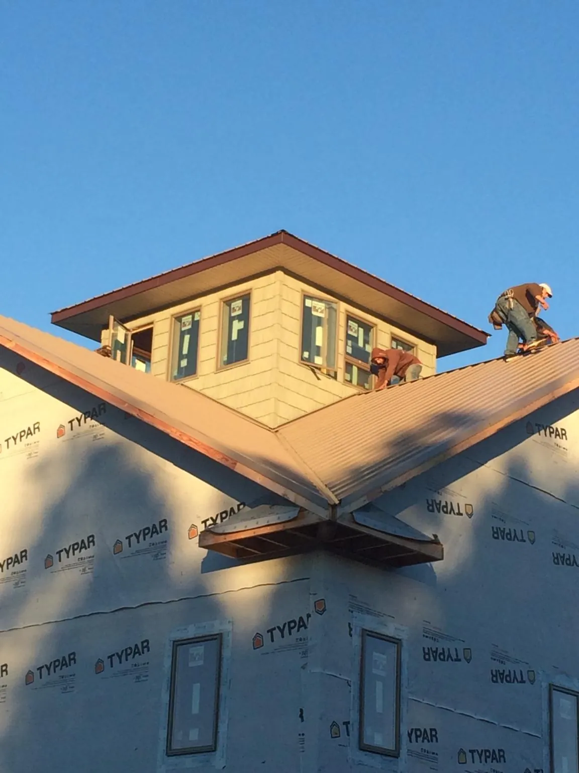 Roofers working around a rooftop cupola on a new metal roof at sunset — Roof Waterproofing in Etoile by Roofing Brothers